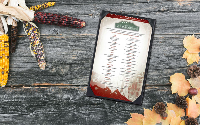 Menu on wooden table with leaves and corn. 
